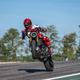 A motorcyclist does a wheelie on a racetrack on the Ducati Monster SP.